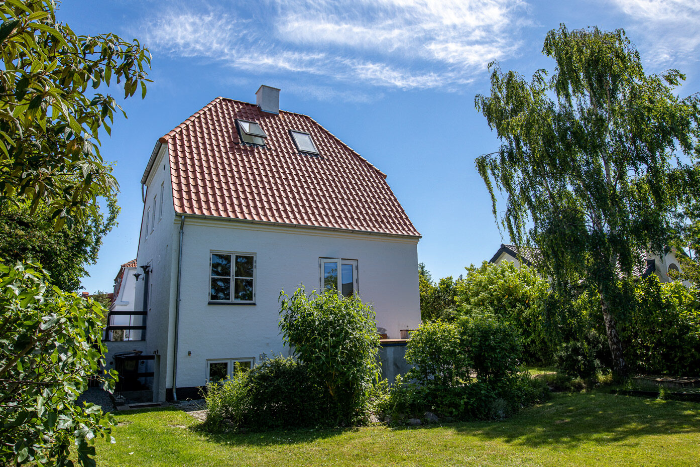 Murermestervillaen set fra haven med nyt rødt tegltag og to ovenlys