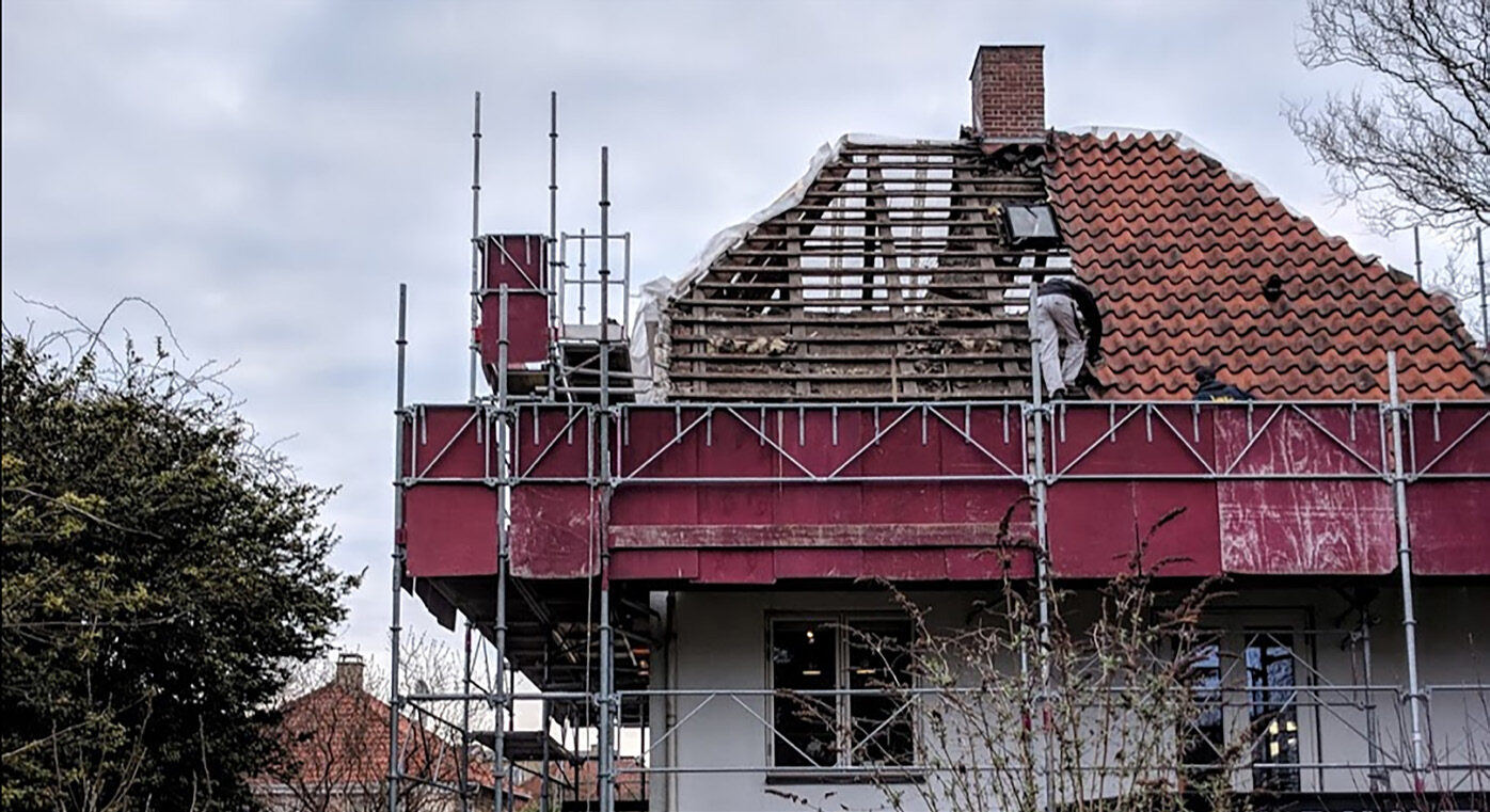 Villaen med stillads og afdækning, hvor den ene tagflade er pillet af