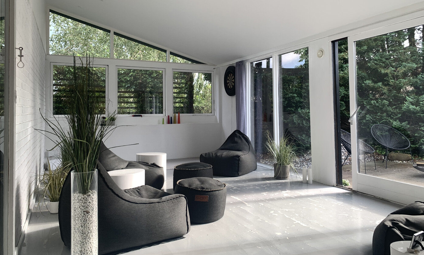 Udestuen indefra med loft til kip, hvidt loft og møbler