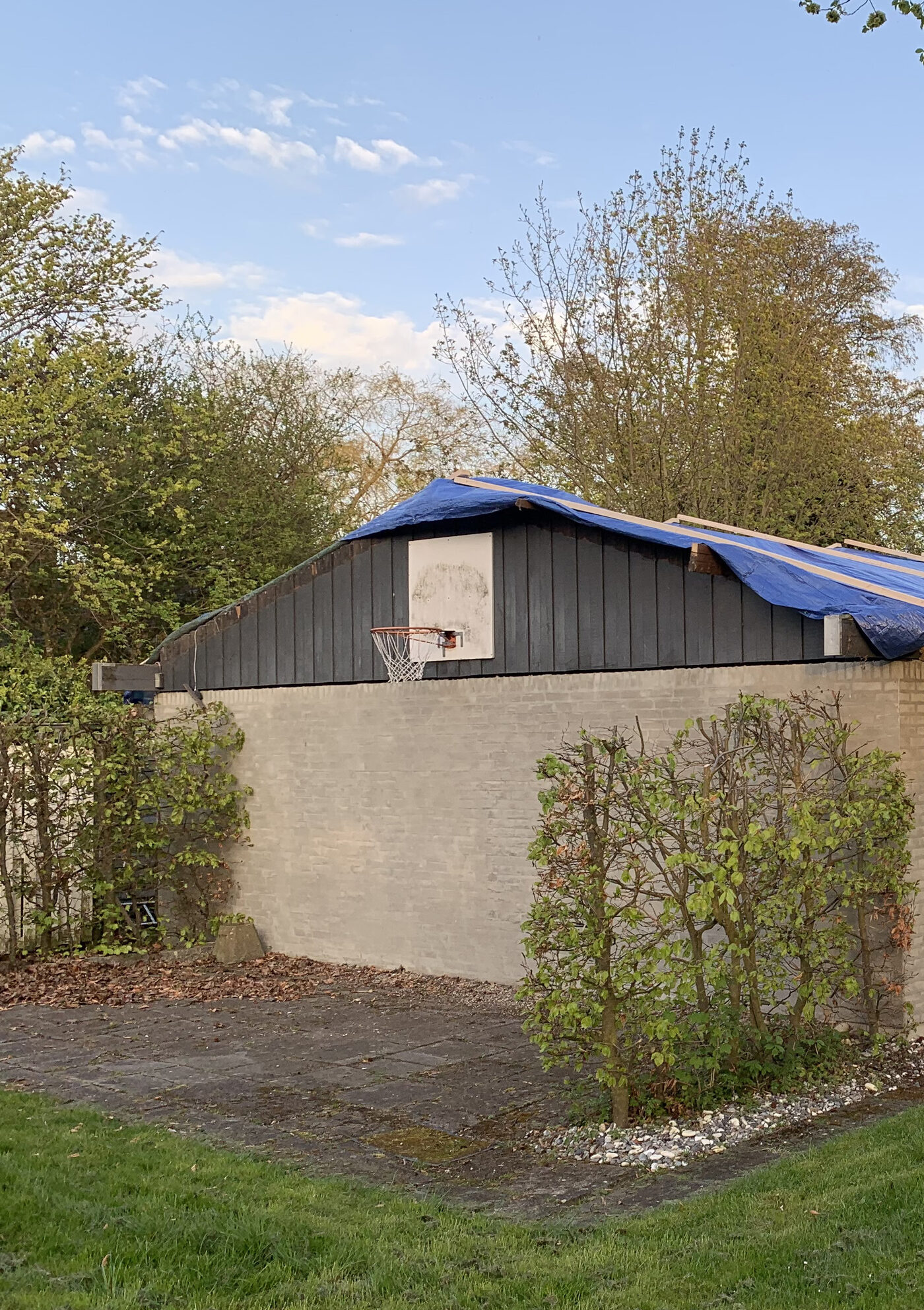 Husets gavlende med carport dækket af blå presenning under tagudskiftningen